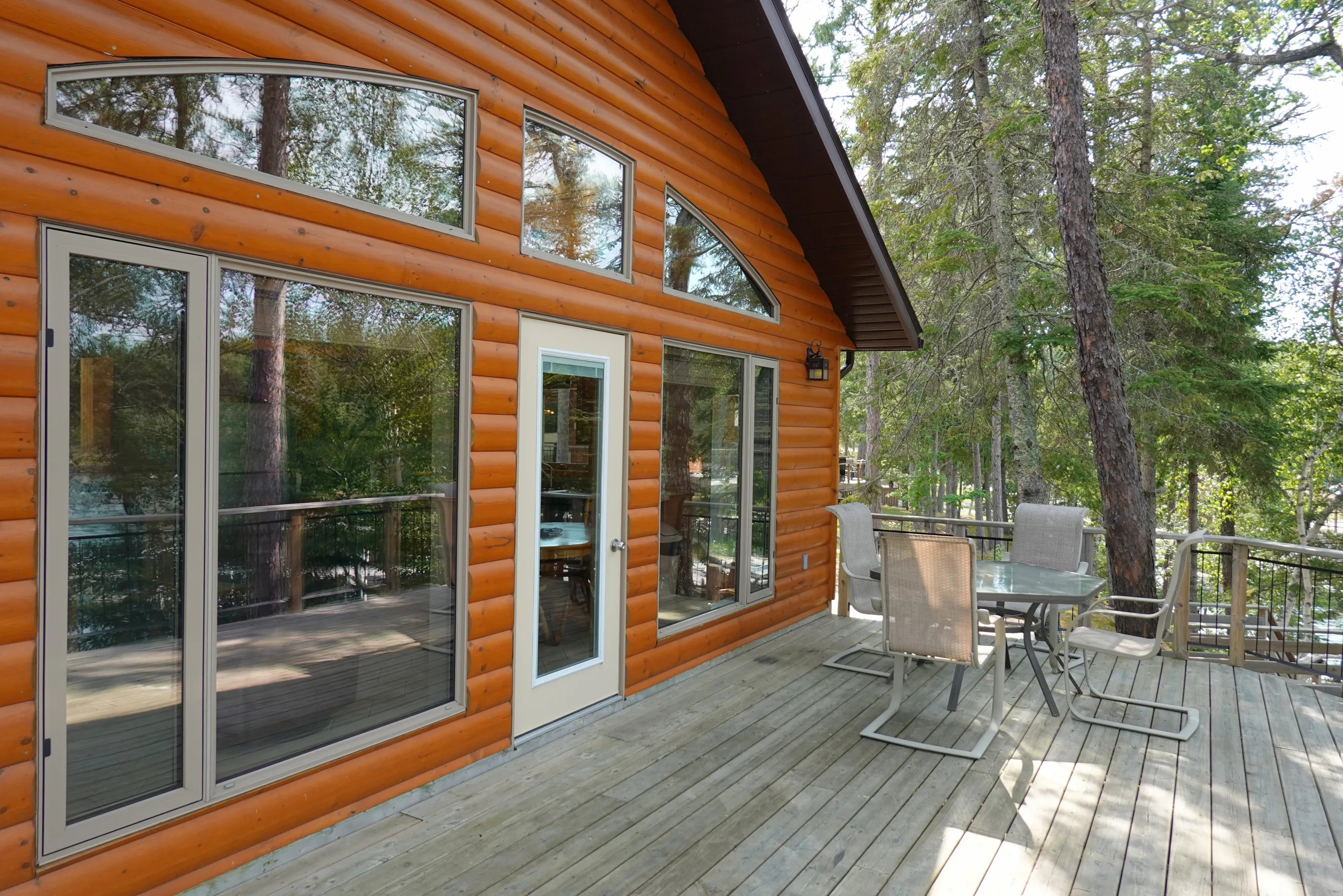 Large deck over looking the lake, with patio table, chairs and a gas grill